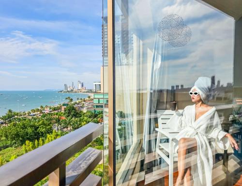 芭堤雅市中心The Bayview Hotel Pattaya的坐在海景阳台上的女人