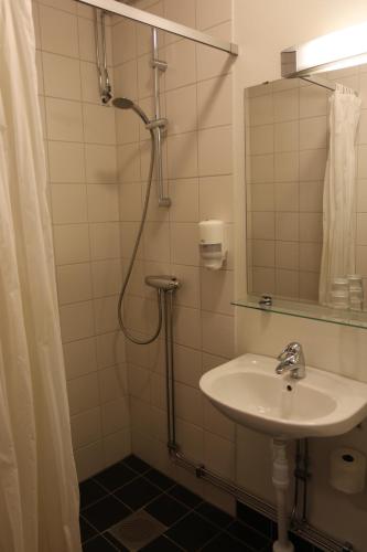 于默奥Hotell Vilja的浴室配有盥洗盆和带镜子的淋浴