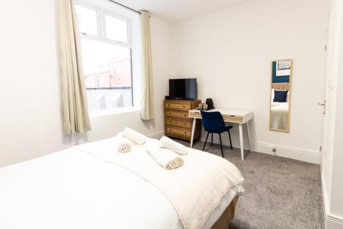 奥尔德姆Suite 2 - Comfy Spot in Oldham Sociable House的一间卧室配有一张床、一张书桌和一个窗户。