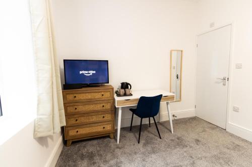 奥尔德姆Suite 2 - Comfy Spot in Oldham Sociable House的客房设有书桌、电视和椅子