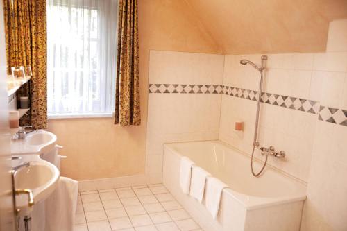 施特拉尔松德加戈霍夫兰德加斯托夫酒店的白色的浴室设有浴缸和水槽。