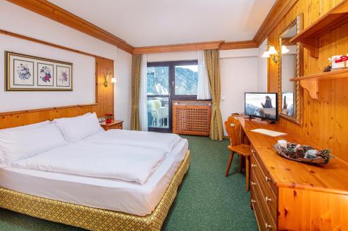 塞尔瓦迪卡多雷妮格丽泰拉酒店的一间卧室配有一张床、一张书桌和一台电视