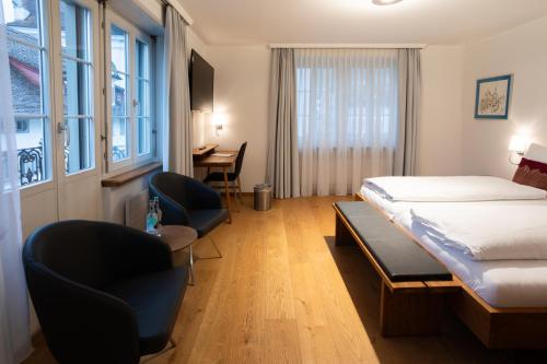 施维茨Wysses Rössli Swiss Quality Hotel的酒店客房配有一张床、椅子和一张书桌