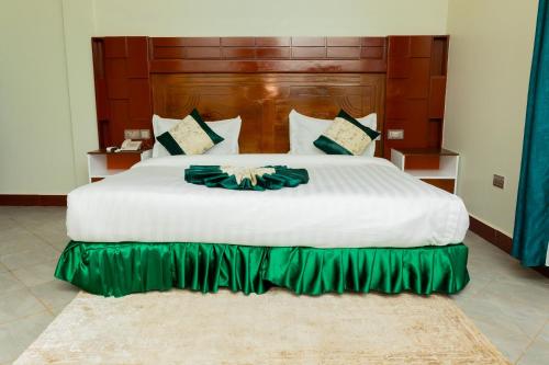 阿鲁沙Kerama Silent Lodge的一间卧室配有一张白色大床和绿色裙子