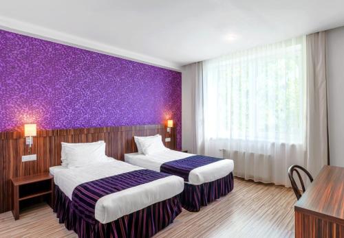 里加Rija VEF Hotel with FREE Parking的酒店客房设有两张床和紫色墙壁。