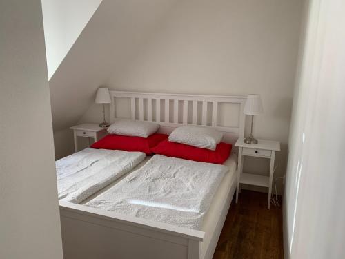 布尔诺Mitte Apartments的一张带两个红色枕头的白色床