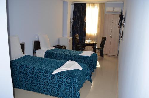 库塔伊西Hotel Okriba的酒店客房设有两张床和一张桌子。