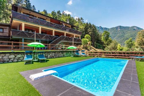 莱德罗Apartments in Pieve di Ledro/Ledrosee 22704的大楼前的带椅子和遮阳伞的游泳池