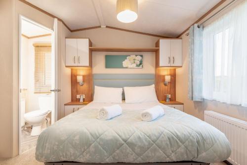 StrathkinnessMaison Verte Lodge 8 Close to St Andrews的一间卧室配有一张床,上面有两条毛巾
