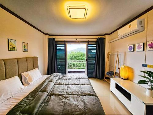 Ban Komo Sip PaetAnda Betong Homestay的一间卧室配有一张床、一张书桌和一个窗户。
