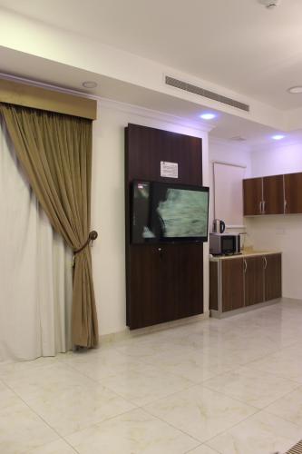 达曼دانة الشرقية للشقق المخدومة بالدمام Danat Al Sharqiah Serviced Apartments的一间配有平面电视和窗帘的客房