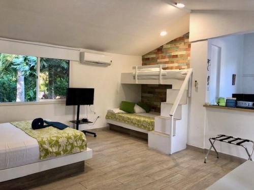 圣安德烈斯Casa de las Flores tropical的一间卧室设有一张床、一张双层床和一个楼梯。