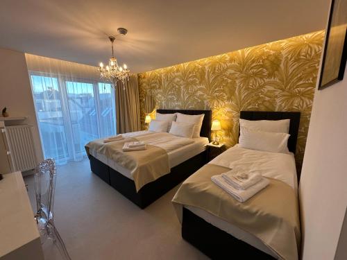 日利纳Villa Mala Praha Experience in the Center of Žilina的酒店客房设有两张床和吊灯。