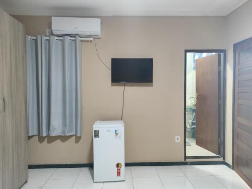 阿拉卡茹Pousada Bem-te-vi的一间设有冰箱和墙上电视的客房
