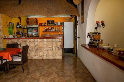 奥奇瓦龙戈Lion's Den Guesthouse Otjiwarongo的餐厅内的酒吧配有桌子和冰箱