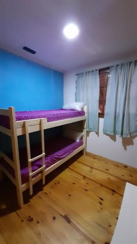 马德普拉塔El Fortin的客房配有带紫色床单的双层床。