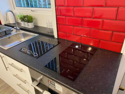 利兹Spacious 4 Bedroom Townhouse的厨房设有水槽和红色瓷砖墙