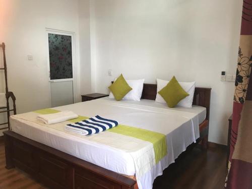 希克杜沃塔马罗海滩度假旅馆的一间卧室配有一张带绿色和白色枕头的大床