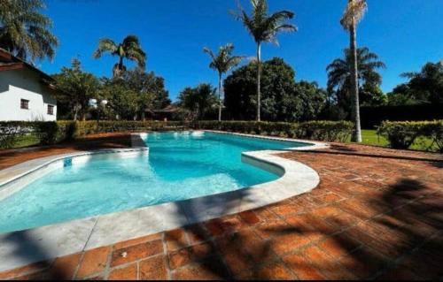 布拉干萨-保利斯塔Chácara Campo Verde的棕榈树庭院内的游泳池