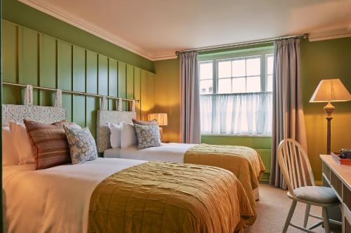 多尔金The White Horse的配有两张床的客房,设有绿色的墙壁和窗户