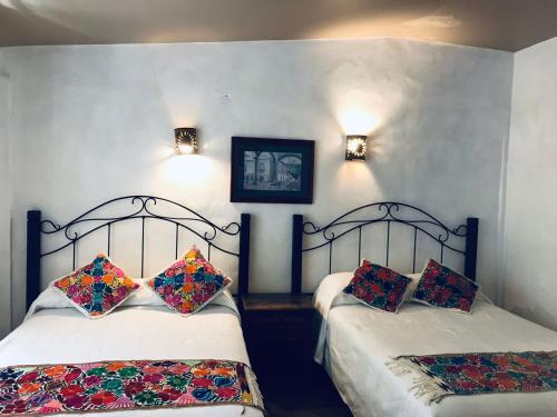 Zinapécuaro de FigueroaPosada Los Colorines的一间卧室配有两张带枕头的床。
