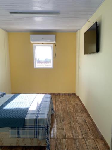 卡舒埃拉保利斯塔Pousada São Benedito的一间卧室设有一张床、一个窗口和一台电视