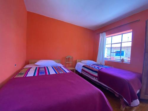 奥科苏尤Orlando´s House的宿舍间的两张床,设有红色的墙壁和窗户。