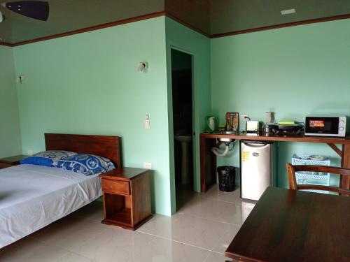 福尔图纳Encanto Arenal lodge的一间卧室配有一张床铺和一张桌子,还设有一间厨房