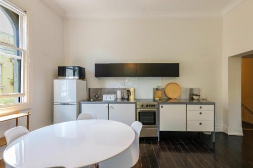 悉尼Surry Hills Chic right on Crown St的厨房配有白色桌子和白色冰箱。