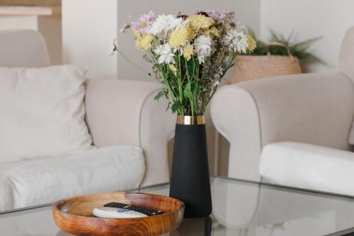 赫尔格达Modern Villa in El Gouna (Private Pool & Garden.)的一张沙发旁的桌子上带鲜花的黑色花瓶