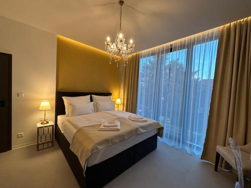 日利纳Villa Mala Praha Experience in the Center of Žilina的一间卧室配有一张带吊灯和大窗户的床。