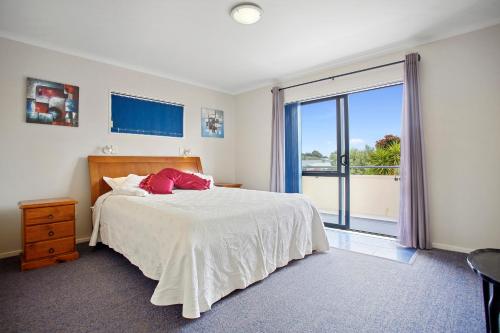 卡蒂卡蒂The Bowentown Bach - Waihi Beach Upstairs Unit的一间卧室设有一张床和一个大窗户