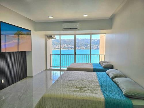 阿卡普尔科departamento con vista al mar的带大窗户的客房内的两张床