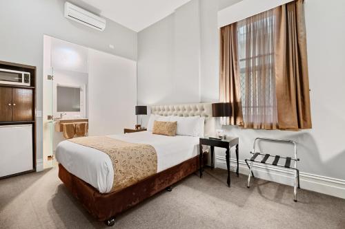 巴拉腊特巴拉瑞特乔治品质酒店 的一间卧室配有一张床、一张书桌和一个窗户。