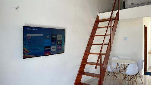 蒂安瓜Villa Suíça, Chalé Mezanino的挂在桌子和椅子旁边的墙上的电视