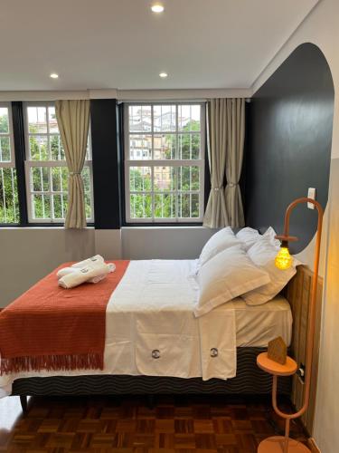 欧鲁普雷图Suíte Horto的一间卧室设有一张大床和两个窗户。