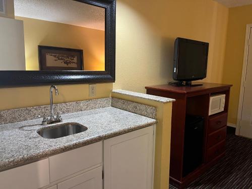 热萨尔弗斯普林斯Red Roof Inn & Suites Sulphur Springs的一间带水槽和镜子的浴室以及一台电视