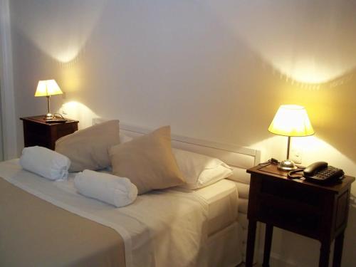 埃斯特角城Green Park Punta del Este的一间卧室配有一张带两盏灯的床和一部电话