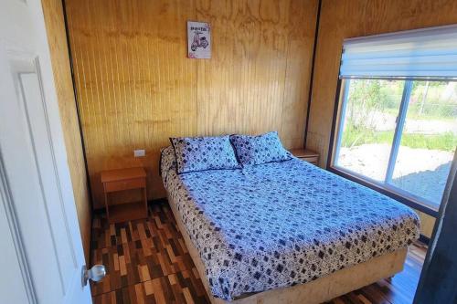 达卡卫Cabaña buck的一间卧室配有一张带蓝色棉被的床和窗户。