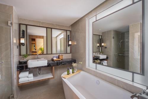 曼谷Nysa Hotel Bangkok Sukhumvit 11的带浴缸、水槽和镜子的浴室