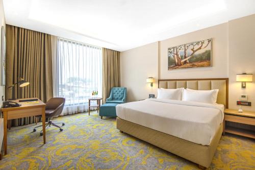 贾朗达尔Golden Tulip Jalandhar的酒店客房配有一张床、一张桌子和一把椅子。