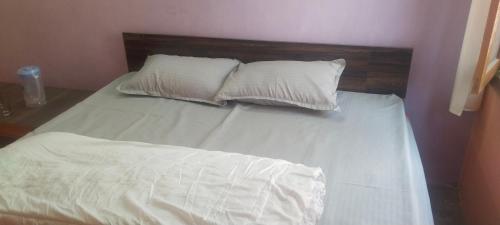 ShamshiKullvi hill homestay的一张带白色床单的床和两个枕头