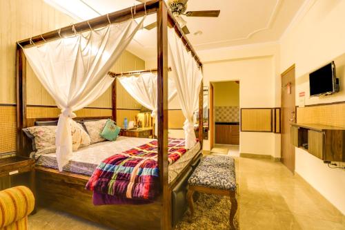 大诺伊达House Of Comfort Greater Noida的一间卧室配有一张天蓬床和一台电视机