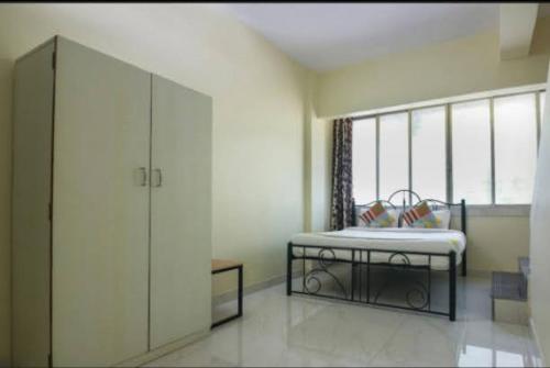 纳威孟买Cozy Stay Kharghar的一间卧室设有一张床和一个大窗户
