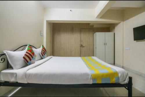 纳威孟买Cozy Stay Kharghar的卧室配有一张带彩色枕头的大型白色床。
