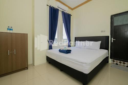 PaciranGrand Kencana Guesthouse near Wisata Bahari Lamongan Mitra RedDoorz的一间卧室配有一张带蓝色窗帘的大床