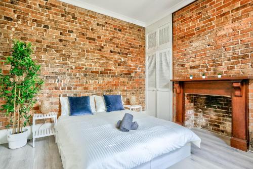 悉尼Comfortable 2 Bedroom House Paddington 2 E-Bikes Included的一间卧室设有砖墙和一张床
