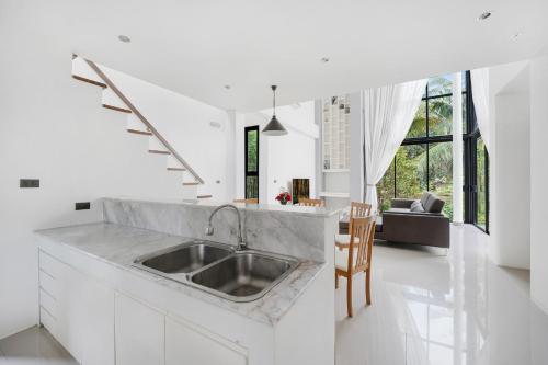 苏梅岛Ana's House的一间带水槽的白色厨房和一个客厅