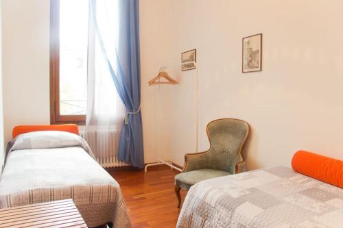 威尼斯Ponte San Lorenzo apartment的客房设有两张床、一把椅子和窗户。
