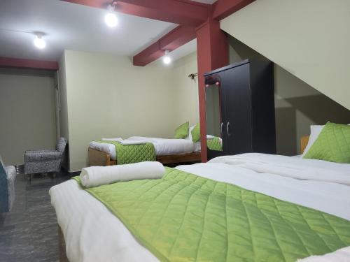西隆Vati guesthouse的一间设有三张床的客房,配有绿色和白色的床单